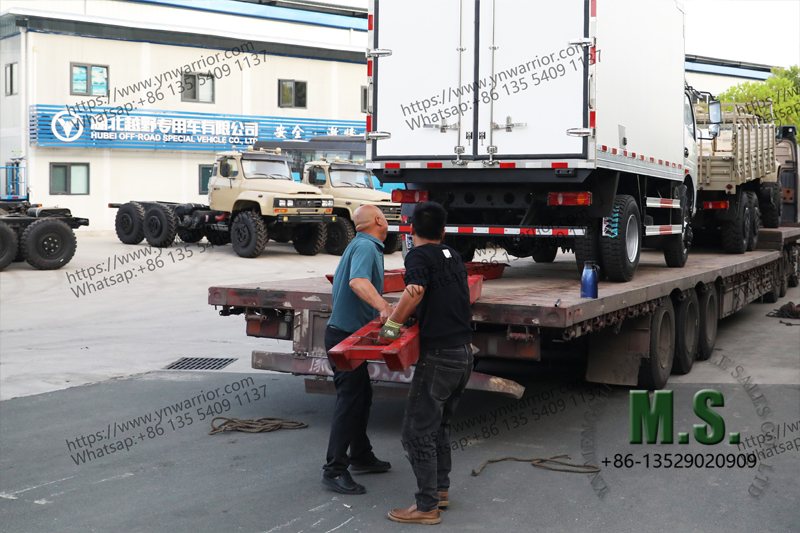 worker are attaching the refrigerator truck on the low bed trailer